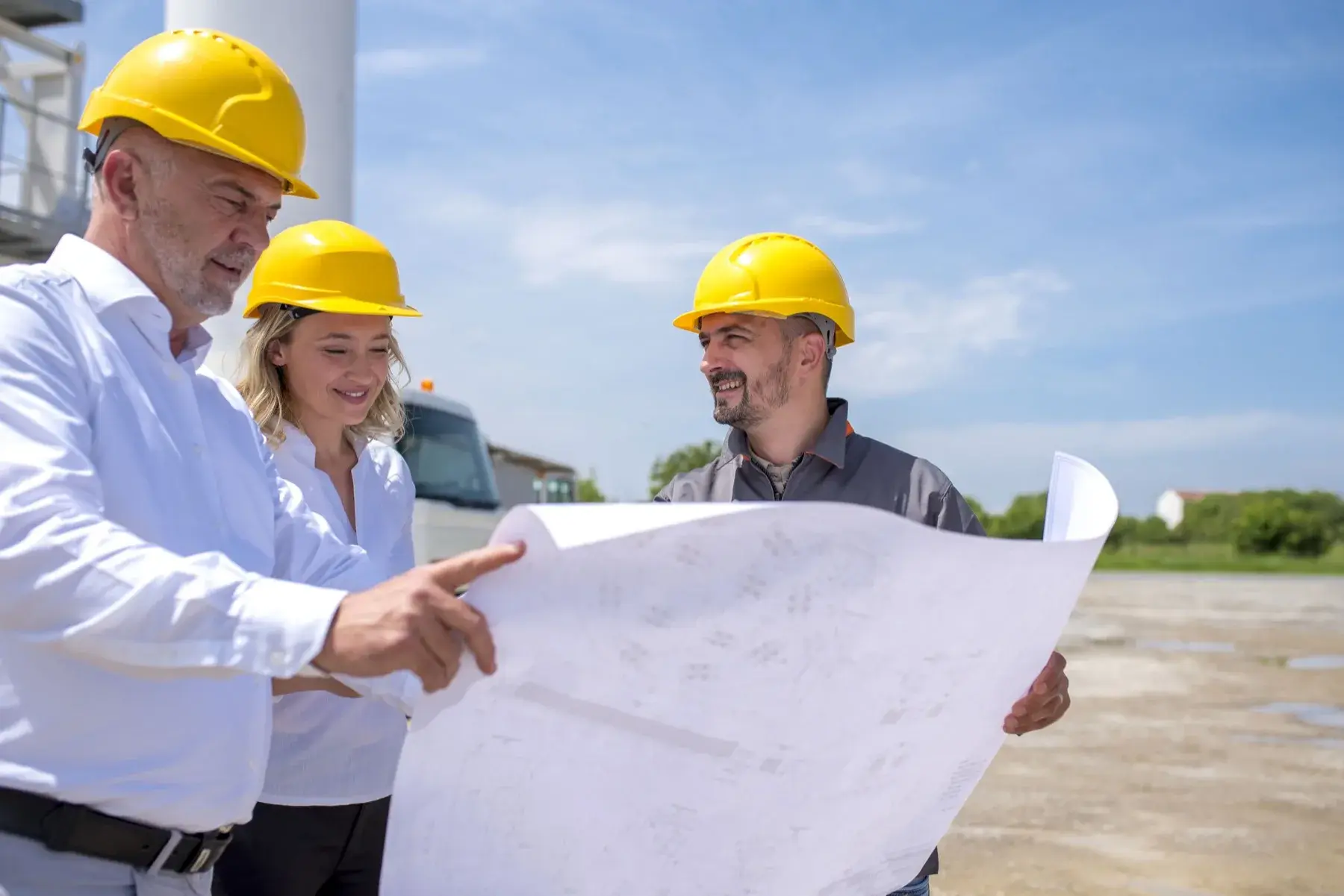 Equipo técnico con casco revisando un plano de instalación en terreno industrial